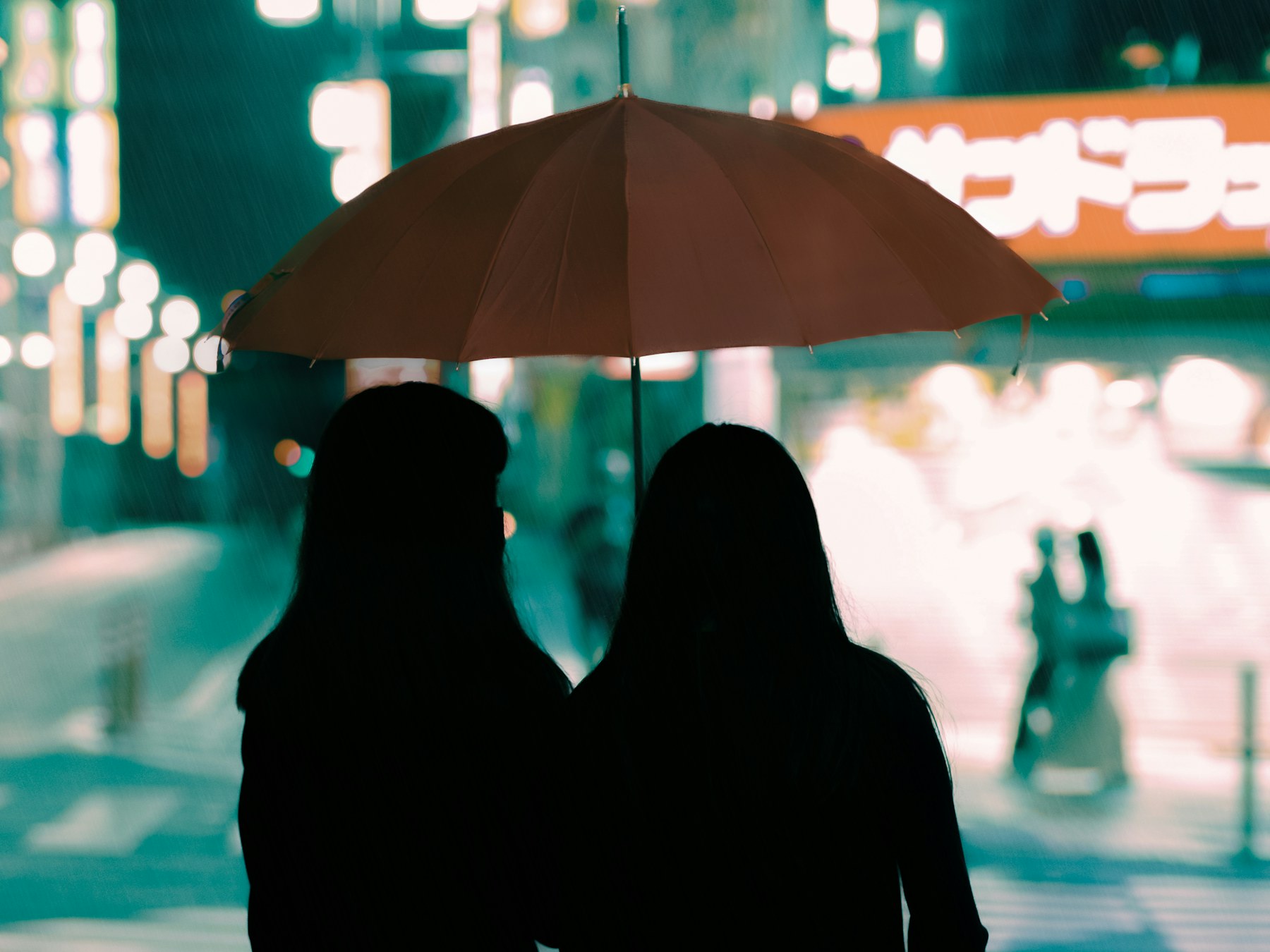 Two people sharing an umbrella on a rainy night